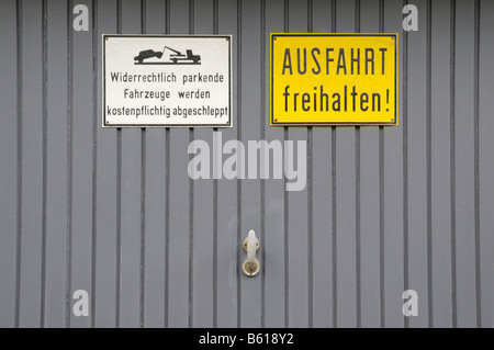 Grauen Garagentor, Schild mit der Aufschrift unrechtmäßig parkende Fahrzeuge werden ab auf Kosten des Besitzers abgeschleppt Stockfoto