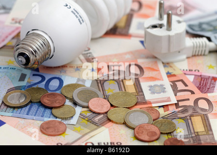 Energiesparende Leuchtmittel und Stecker auf Euro-Banknoten und Euro-Münzen, Energiepreise Stockfoto