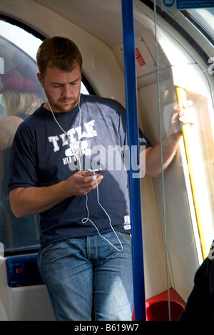 Mann ein Ipod auf die Londoner U-Bahn u-Bahn-System in London England anhören Stockfoto