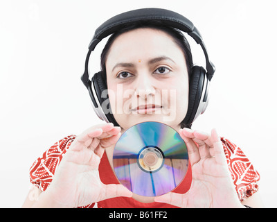 asiatische Frau indischer Herkunft mit Kopfhörer und halten einer Compact disc Stockfoto