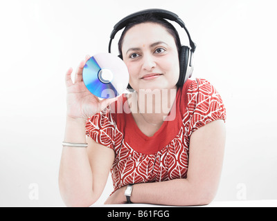 asiatische Frau indischer Herkunft mit Kopfhörer und halten einer Compact disc Stockfoto