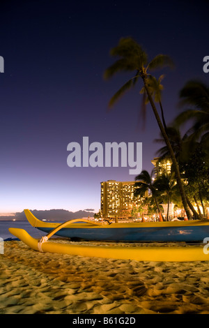 Ein Ausleger-Kanu am Strand von Waikiki in Honolulu, Oahu, Hawaii in der Abenddämmerung. Stockfoto