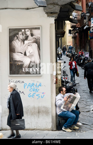 Straßenszene in Quartier Toledo, Mann liest die Papiere, die alte Frau unter ein Poster eines Modells, bröckelnde Fassade, Naples Stockfoto