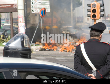 Hausmüll Feuer fängt in der sommerlichen Hitze, manchmal spontan, beobachtet von einem Polizisten oder Carabiniere, Neapel Stockfoto