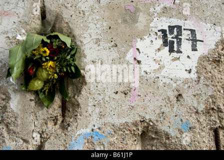 Blumen in einem Loch in der Mauer, Berliner Mauer in der Bennauer Straße, Teil des Denkmals für den Bau der Berliner Mauer, Berlin Stockfoto