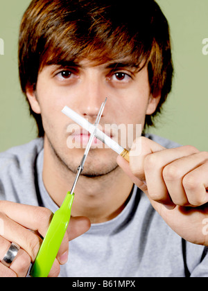 Junger Mann zerschneiden eine Zigarette Modell veröffentlicht Stockfoto