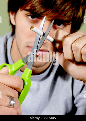 Junger Mann zerschneiden eine Zigarette Modell veröffentlicht Stockfoto