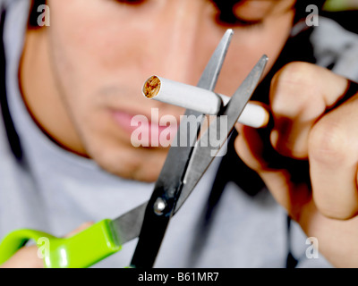 Junger Mann zerschneiden eine Zigarette Modell veröffentlicht Stockfoto