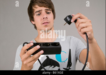 Junger Mann mit einem Verlängerungskabel Stockfoto