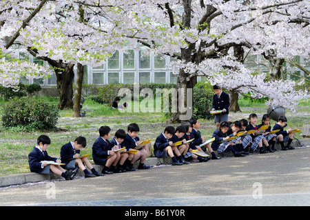 Schulkinder in der Uniform eines elitären Grundschule während des aktiven Lernens im Botanischen Garten in Kyoto, Japan, Stockfoto