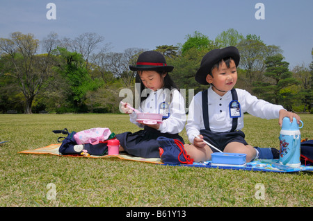 Schülerinnen und Schüler tragen Schuluniform und Namensschild ein Elite-Grundschule in der Mittagspause Essen mit Stäbchen Stockfoto