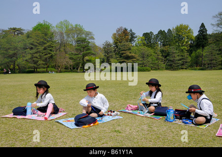 Schülerinnen und Schüler tragen Schuluniform und Namensschild ein Elite-Grundschule in der Mittagspause Essen mit Stäbchen Stockfoto