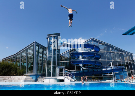 Schwimmer Tauchen von einem Sprungbrett vor einer Wasserrutsche in den Außenpool im Triamare Baden-Komplex in Stockfoto