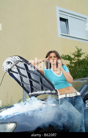 Junge Frau warten auf Hilfe, lehnte sich gegen ihr aufgeschlüsselt und Rauchen Auto, jemanden um Hilfe telefonieren Stockfoto