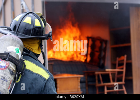 Ein Feuerwehrmann bereit, ein Feuer in einem Container voller Möbel zu kämpfen Stockfoto