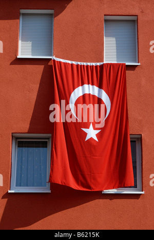 Türkische Flagge hängt an der Wand eines Mehrfamilienhauses Stockfoto