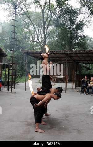 Chinesische Miao ethnischen Minderheit der jungen Männer die traditionelle Feuer Straßenmusik durch das Lecken und schlucken Flammen Touristen zu unterhalten Stockfoto