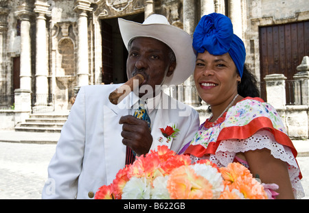 Frau mit Blumen und ein Mann mit einer Zigarre posieren für touristische Fotos, Altstadt von Havanna, Kuba, Karibik Stockfoto