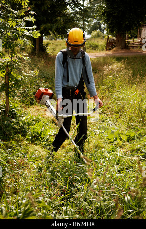 Junger Bauer mäht den Rasen mit einem Rasentrimmer, Othenstorf, Mecklenburg-Western Pomerania, Deutschland, Europa Stockfoto