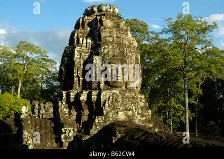 Turm mit Steinrelief eines Gesichts der Bayon-Tempel in Angkor Thom, mit Wald, Siem Reap, Kambodscha Stockfoto