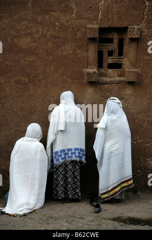 Äthiopische orthodoxe Frauen tragen weiße Umhänge, beten vor der Wand der monolithischen Beta Medhane Alem Kirche, Lalibela Stockfoto