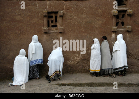 Äthiopische orthodoxe Frauen tragen weiße Umhänge, beten vor der Wand der monolithischen Beta Medhane Alem Kirche, Lalibela Stockfoto