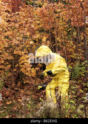 43 Jahre alten asiatischen Mann in einem Hazmat-Anzug und Gasmaske im Freien mit den Herbstfarben und Laub Stockfoto