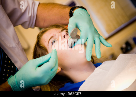 Vierzehn Jahre alten Mädchen, das ihre Zähne durch ihre nationalen Gesundheitsdienst NHS Kieferorthopäden unter einer Besetzung von den oberen Zähnen geprüft Stockfoto