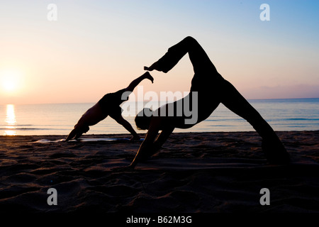 Zwei Menschen praktizieren Yoga am Strand Stockfoto