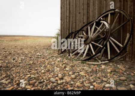 Wagenräder lehnte sich gegen die Wand eines verlassenen Gebäudes, Old Trail Town, Cody, Wyoming, USA Stockfoto