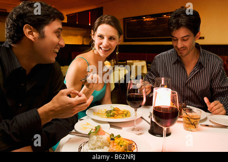 Zwei junge Männer mit einer jungen Frau in einem Restaurant Essen Stockfoto