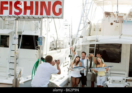 Rückansicht einer Person fotografieren von vier Freunden Tote Fische halten und Lächeln Stockfoto