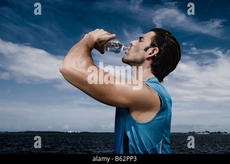 Seitenansicht von einem jungen Mann Trinkwasser aus einer Wasserflasche Stockfoto
