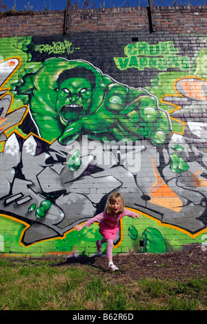 Mädchen erscheinen zu fliehen aus einem Graffiti-Bild auf eine Wand unglaubliche Hulk Flucht gespritzt Stockfoto