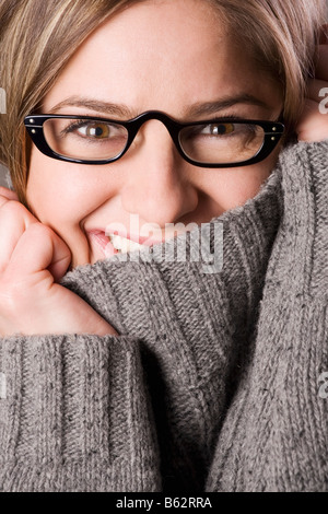 Porträt einer jungen Frau verbirgt ihr Gesicht mit Rollkragen Kragen und lächelnd Stockfoto