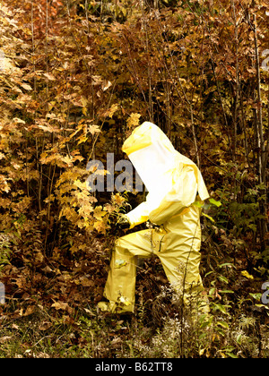 43 Jahre alten asiatischen Mann in einem Hazmat-Anzug und Gasmaske im Freien mit den Herbstfarben und Laub Stockfoto