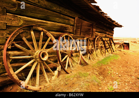 Wagenräder lehnte sich gegen die Wand eines verlassenen Gebäudes, Old Trail Town, Cody, Wyoming, USA Stockfoto