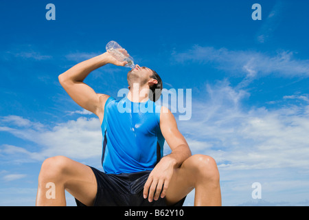 Niedrigen Winkel Blick auf einen jungen Mann Trinkwasser aus einer Wasserflasche Stockfoto