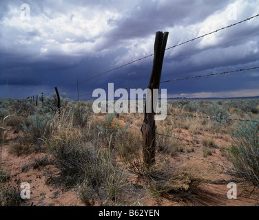 USA New Mexico Sommer Gewitterwolken über dem Stacheldrahtzaun entlang Route 380 in der Nähe von Socorro Stockfoto