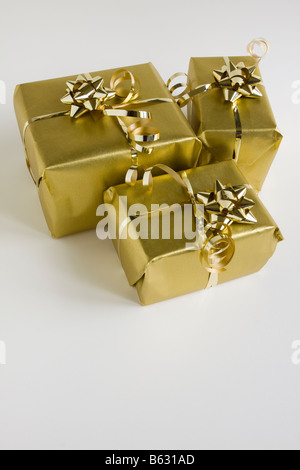 Eine Gruppe von drei Parzellen Geschenk in Goldpapier eingewickelt