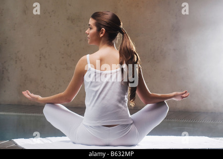 Rückansicht einer jungen Frau am Pool zu meditieren Stockfoto