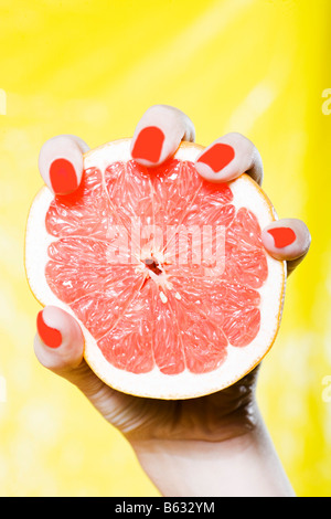 Kaukasische Frau Hand hält eine Grapefruit-Studio auf gelbem Hintergrund Stockfoto