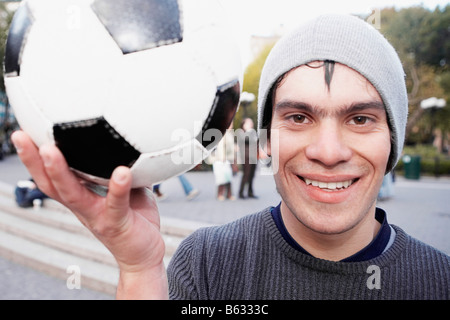 Porträt eines jungen Mannes hält einen Fußball und lächelnd Stockfoto