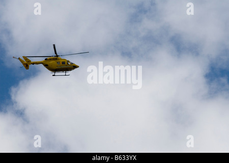 Eine gelbe Luft Rettungshubschrauber vor einem bewölkt aber blauen Himmel Stockfoto