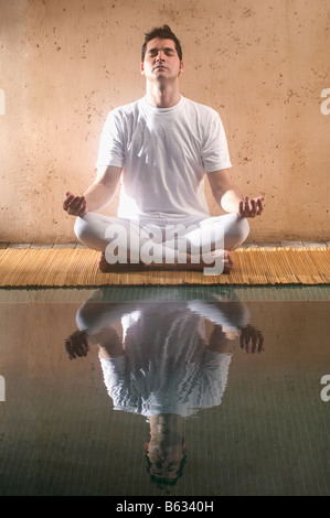 Mitte erwachsenen Mannes praktizieren Yoga am Pool Stockfoto