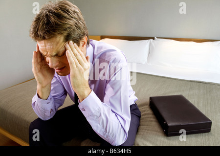 Geschäftsmann, sitzen auf dem Bett und leiden unter Kopfschmerzen Stockfoto