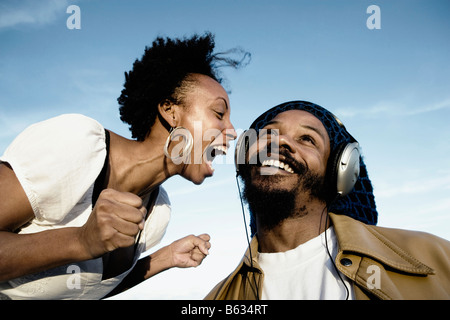 Mitte erwachsener Mann Musik zu hören und eine junge Frau schreiend vor ihm Stockfoto