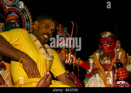 Ein Safran bedeckt Mann sitzt von Hindu-Gottheiten am Ende eines Feuerlauf-Festivals in Bangalore, Indien. Stockfoto