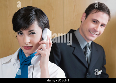 Nahaufnahme der Empfangsdame reden über das Telefon und ein Geschäftsmann hinter ihr stehen Stockfoto