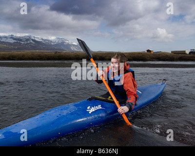 Teenager-Mädchen Kajakfahren im Fluss mit Oraefajokull Gletscher im Hintergrund, Ost-Island Stockfoto